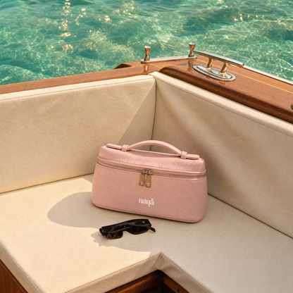 Bloomy Bag rose posée sur la banquette d'un bateau à côté de lunettes de soleil