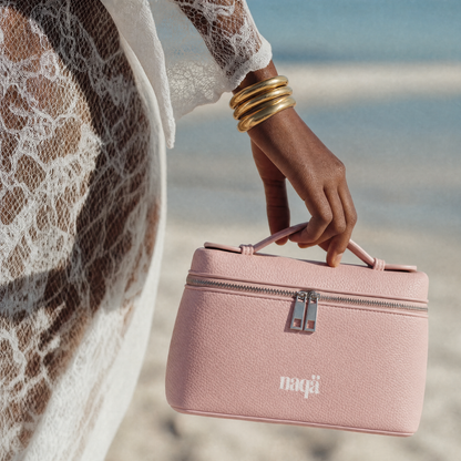 Main attrapant la pochette Bloomy Bag rose sur la plage